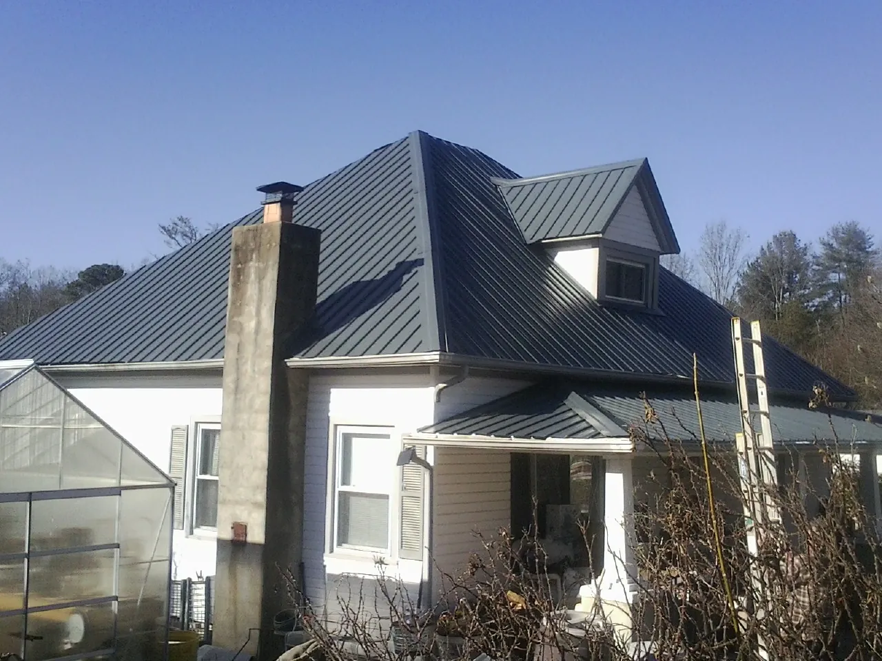 Dark blue standing seam metal roof on a white farmhouse with dormer — Slate & Tile Roof Repair by Roofing Brothers in Grayland