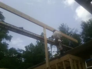 Carpenter setting a ridge beam over a new addition frame — Ice Dam Removal by Roofing Brothers in Grayland