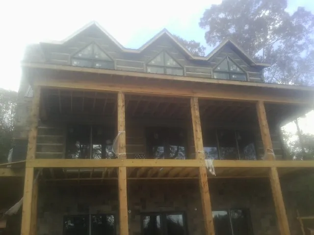 Dormers and porch framing on a large log home under construction — Roof Coating work by our crew in Grayland