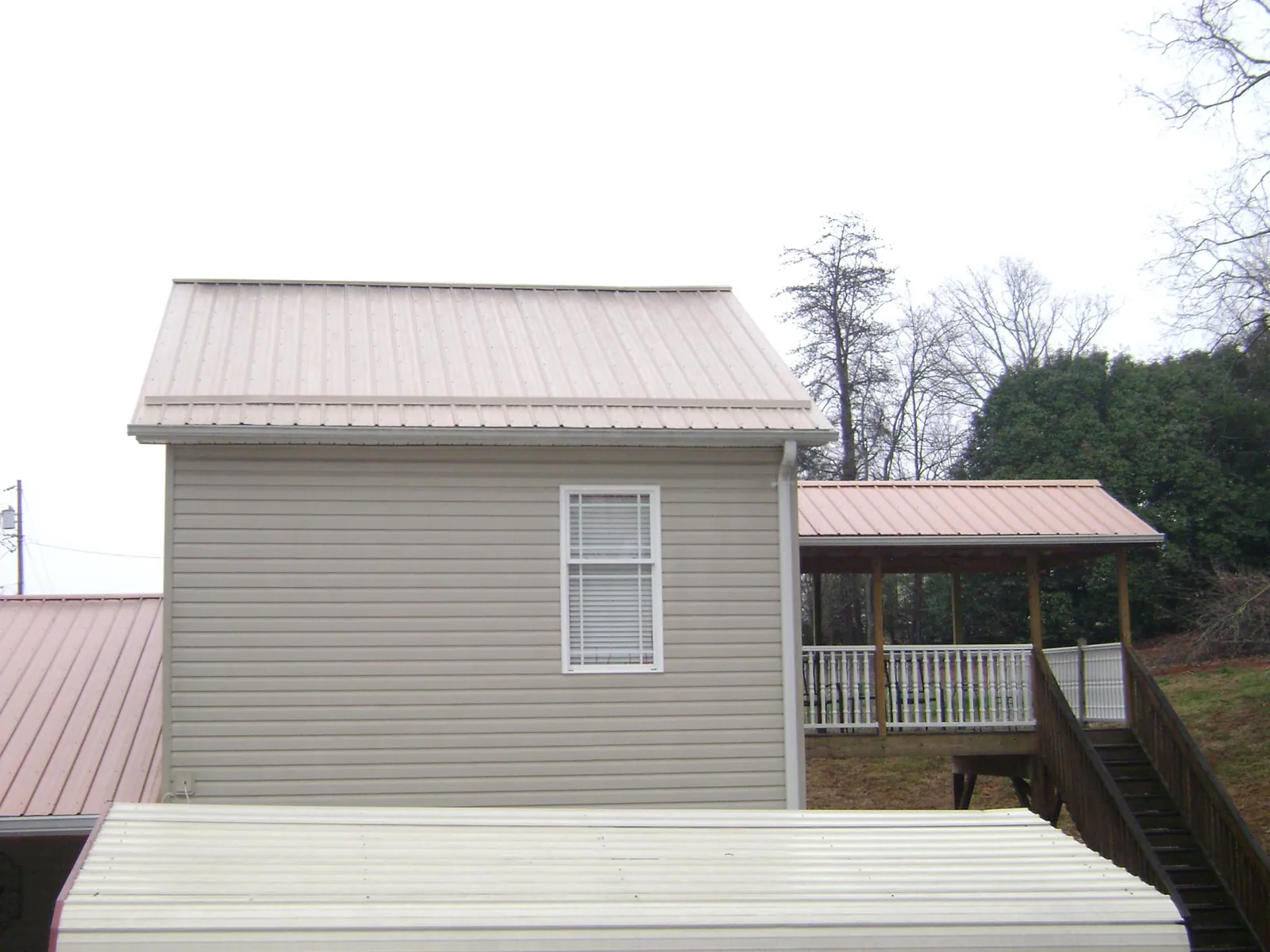 Tan metal roofs on a two story addition and attached porch, from a Roof Replacement job in Grayland