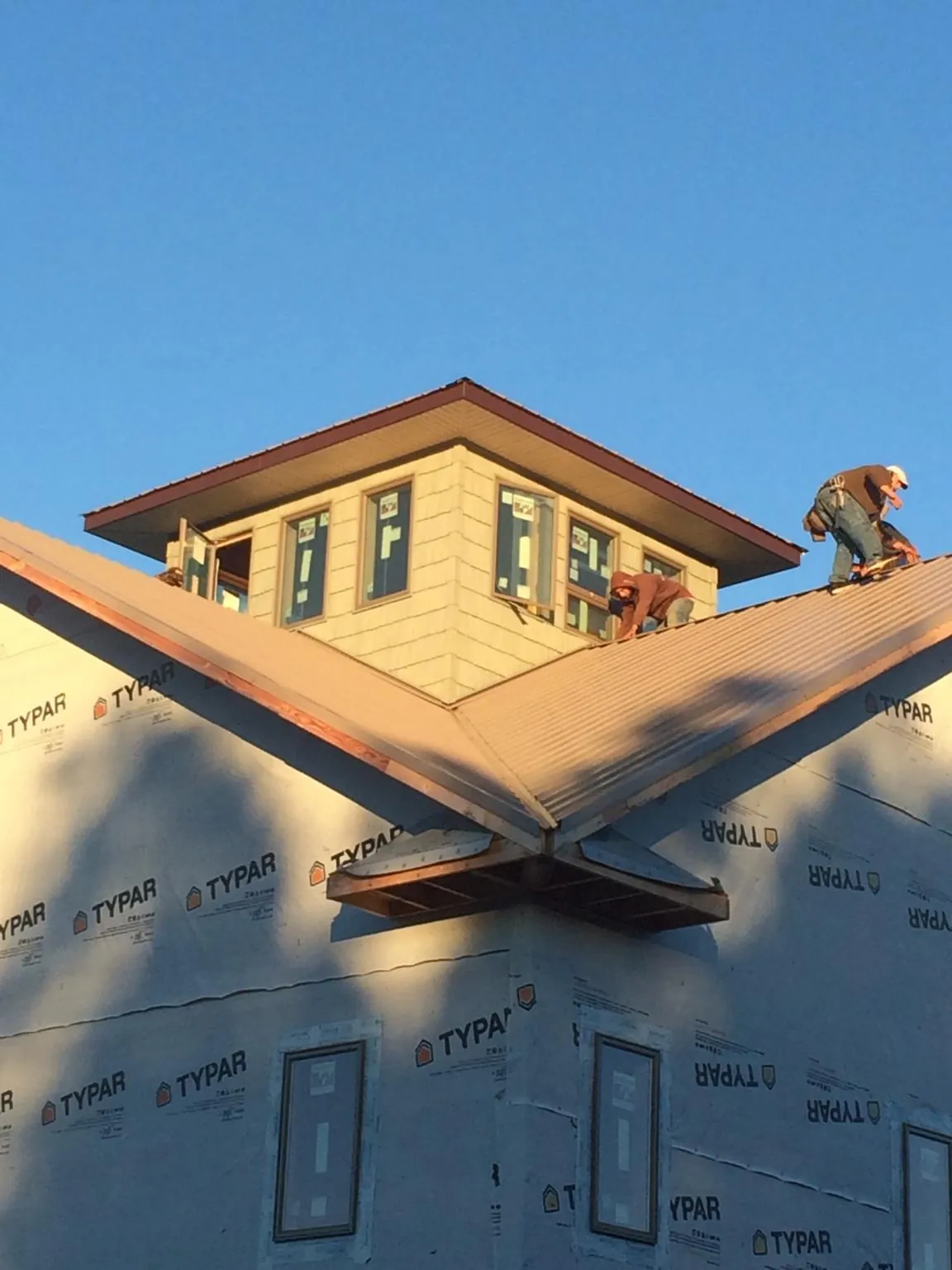 Roofers working around a rooftop cupola on a new metal roof at sunset — Roof Waterproofing in Grayland by Roofing Brothers